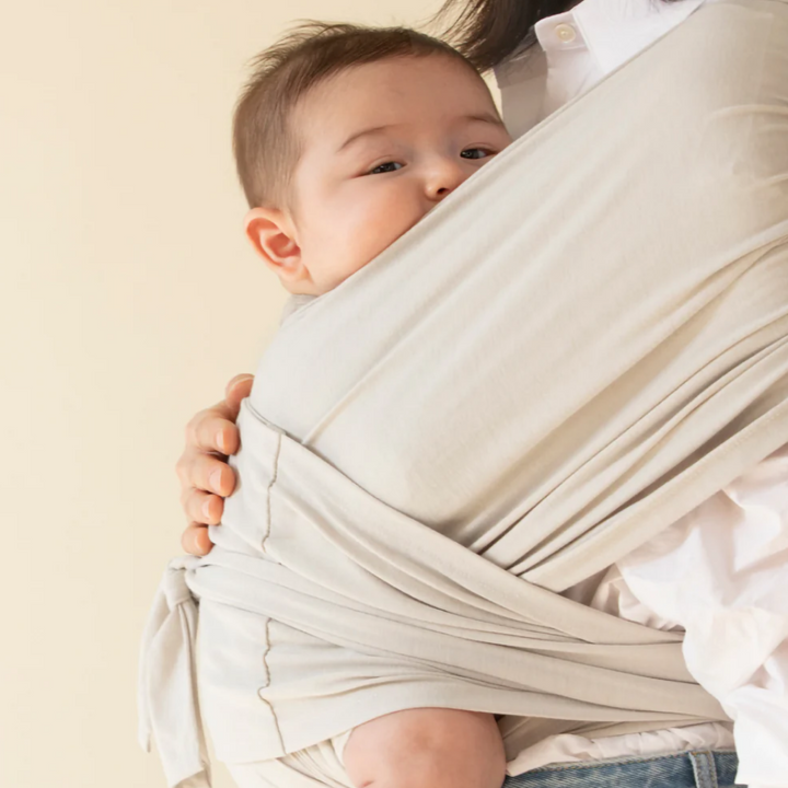 Ouder met baby in ergonomische draagdoek, heeft handen vrij voor activiteiten terwijl baby comfortabel is.