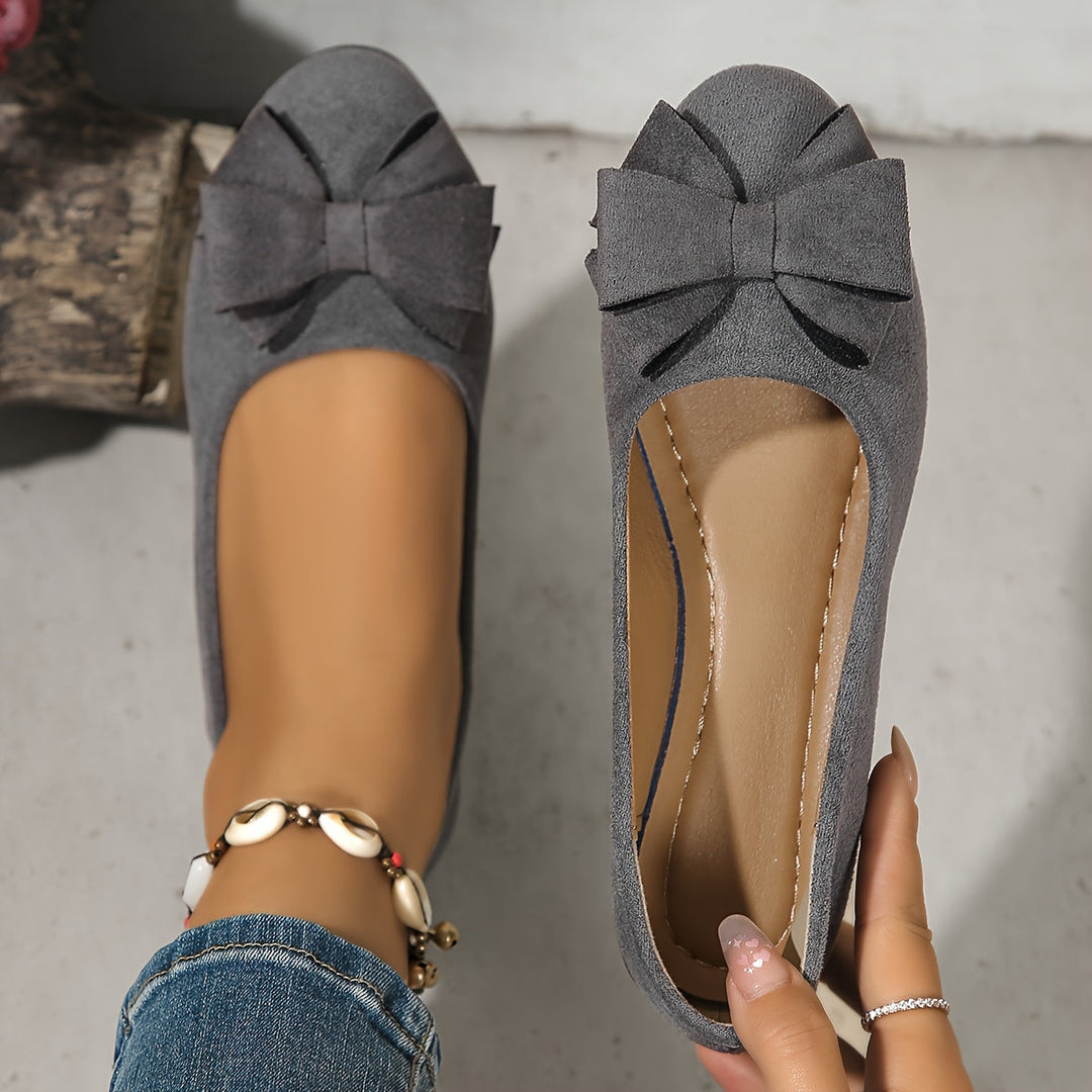 Zijaanzicht: chique dames instappers, elegante sleehak ballerina's met strik detail.