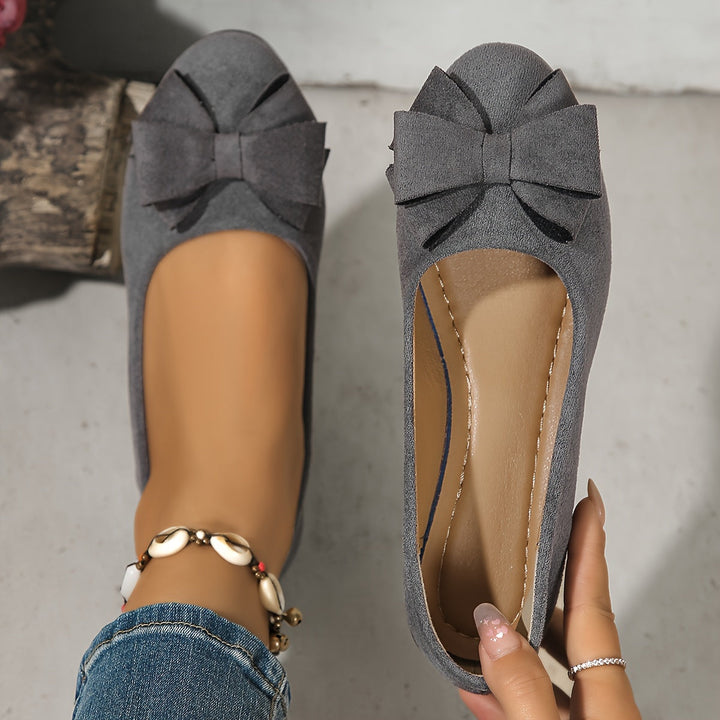 Zijaanzicht: chique dames instappers, elegante sleehak ballerina's met strik detail.