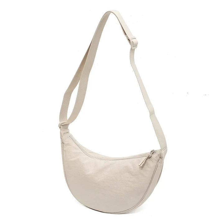 Compacte canvas dumpling tas voor dames, veelzijdig te dragen als schouder- of crossbody tas.