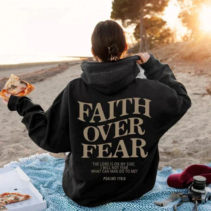 Model draagt trendy uniseks hoodie 'Geloof Over Angst'. Inspirerende boodschap & casual mode.