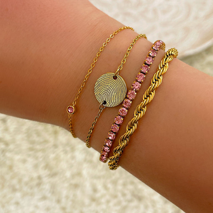 Sierlijke gouden armband met glanzende ronde geboortesteen; een tijdloos en elegant dames sieraad.