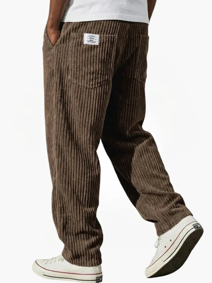 Close-up: elastische tailleband met trekkoord op beige loose fit corduroy herenbroek. Toont detail en comfort.