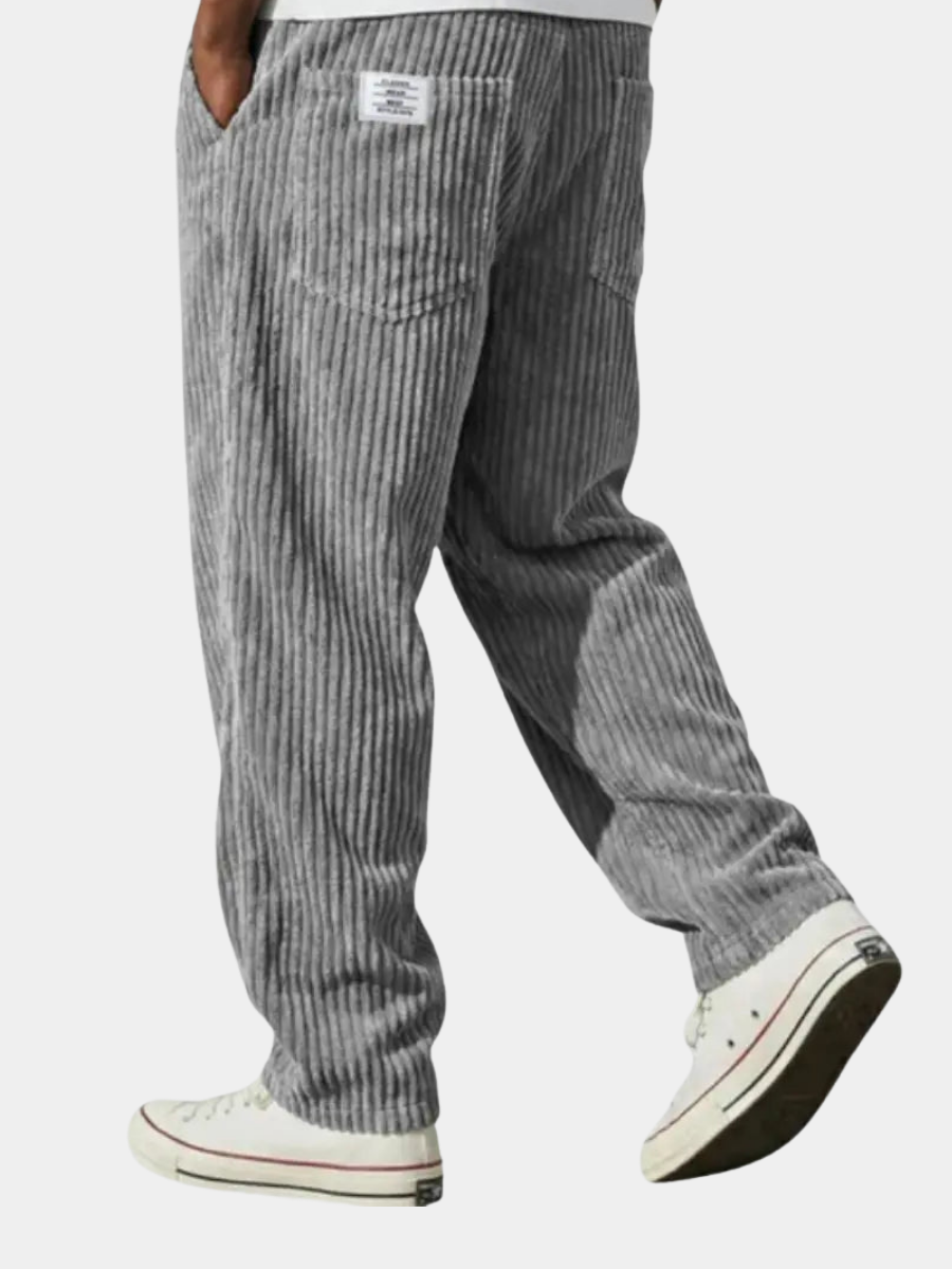 Model draagt casual beige loose fit heren corduroy broek. Toont comfortabele pasvorm en elastische tailleband.