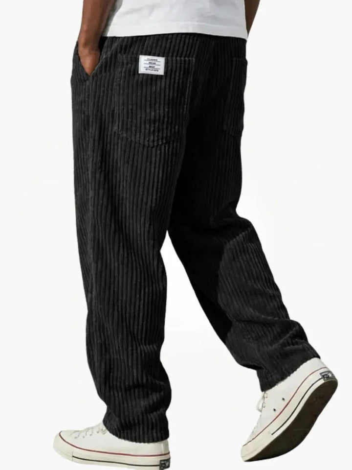 Achterkant van zwarte heren corduroy broek met loose fit. Met praktische zakken en comfortabele elastische tailleband.