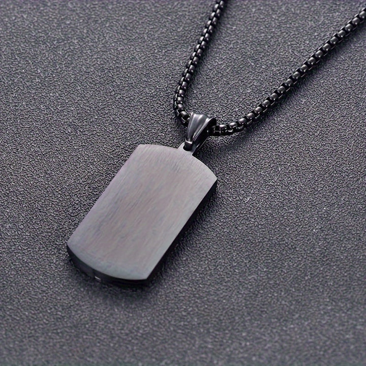Herenketting met zwarte vintage roestvrijstalen hanger gedragen door man, stoer en modieus heren sieraad.