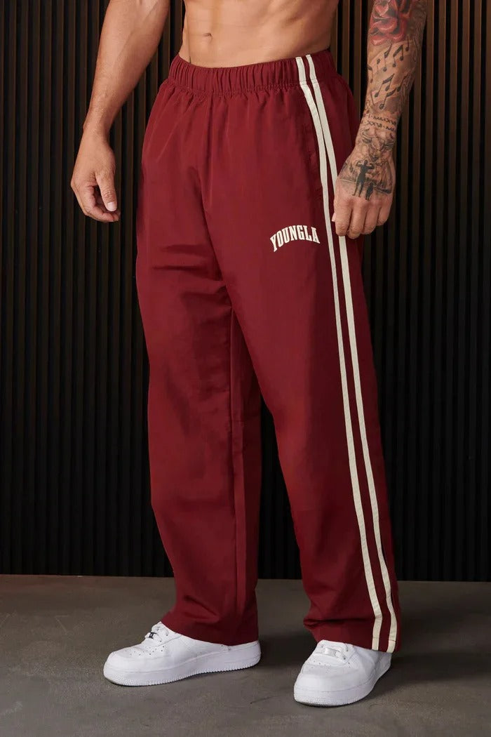 Zwarte heren sportbroek met dubbele witte strepen, flexibel en ademend voor training en vrije tijd.