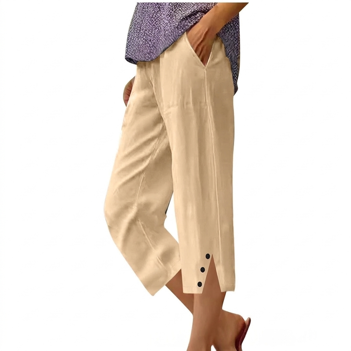 Model draagt een comfortabele, effen damesbroek met hoge taille, relaxte pasvorm en zakken.