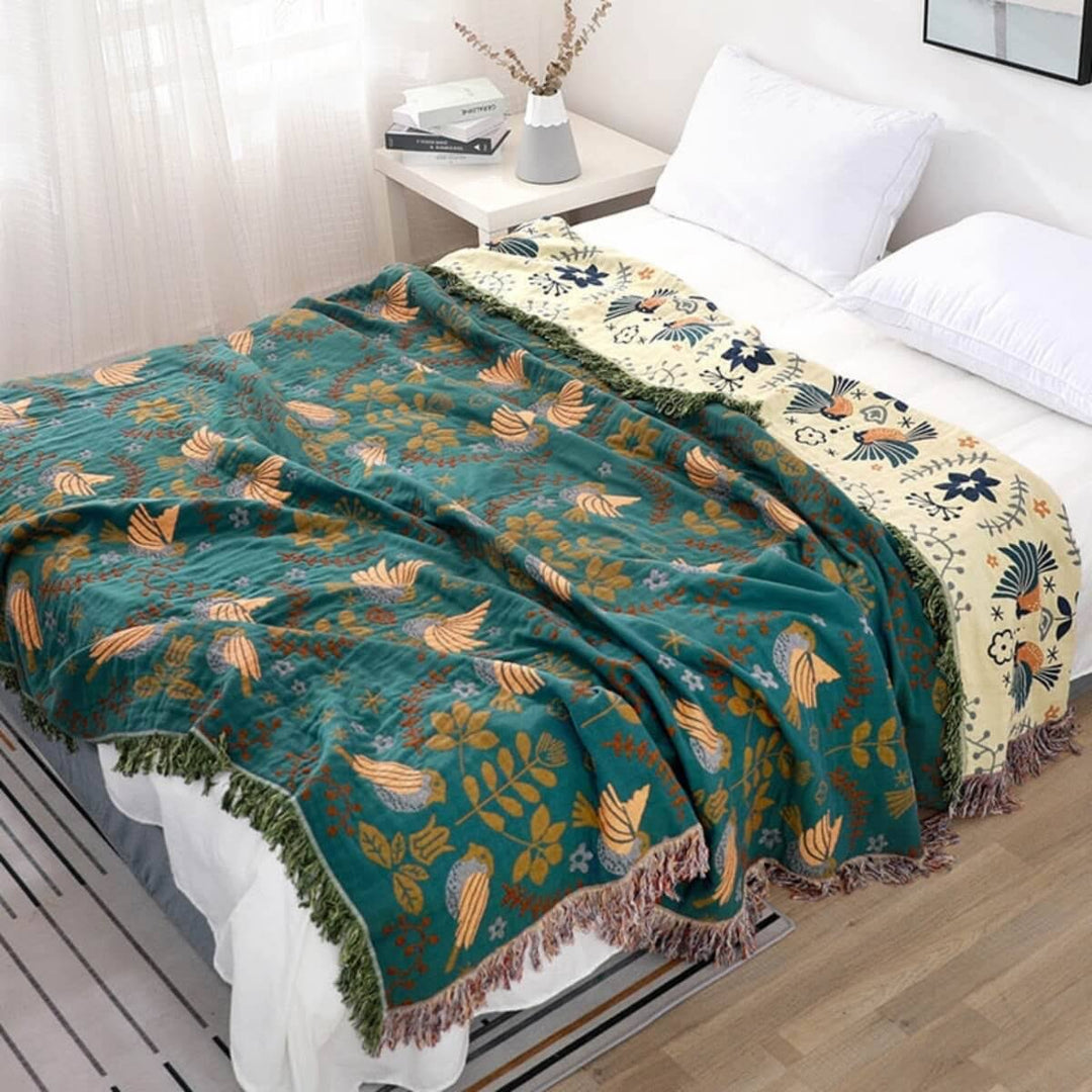 Omkeerbare Scandinavische plaid met stijlvolle vogelprint. Groene en rood-beige zijde voor een warme woondecoratie.