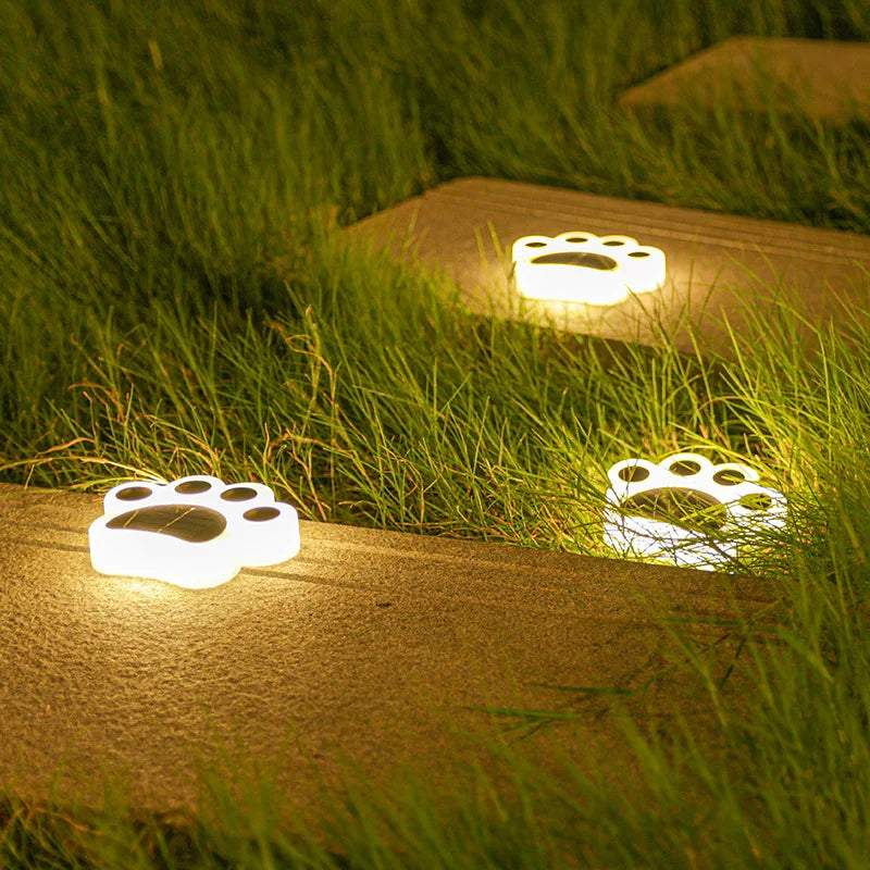 Sfeervolle draadloze Solar Paws grondspots verlichten tuinpad 's avonds met warm LED licht.