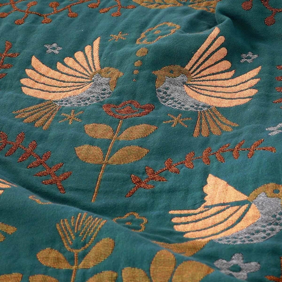 Gezellige katoenen deken met Scandinavische vogelprint. Omkeerbare plaid in groen en rood-beige, ideaal als bankdeken.