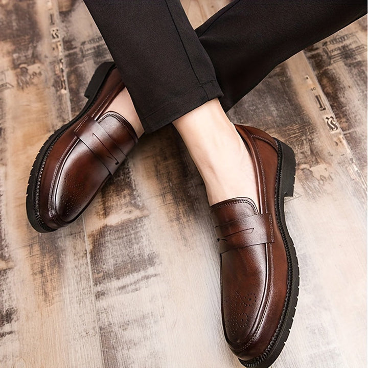 Gedetailleerde bruine penny loafers voor heren met elegant brogue patroon, perfect als stijlvolle instapper.