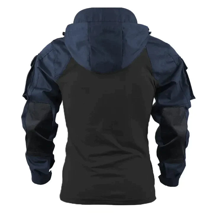 Man poseert in donkere tactische hoodie met capuchon; praktische en casual herenkleding, ideaal voor koude dagen.