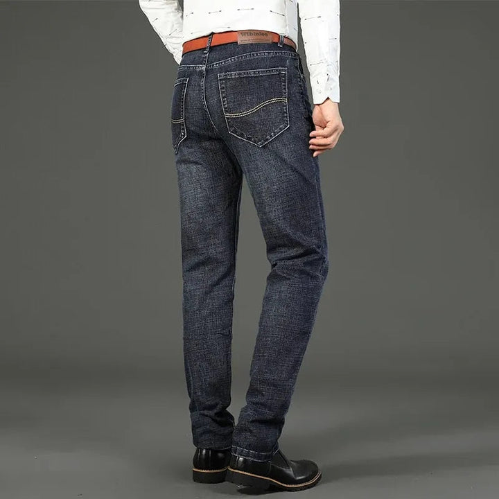 Mannelijk model draagt klassieke rechte blauwe herenjeans. Comfortabele straight-leg spijkerbroek, tijdloze stijl.