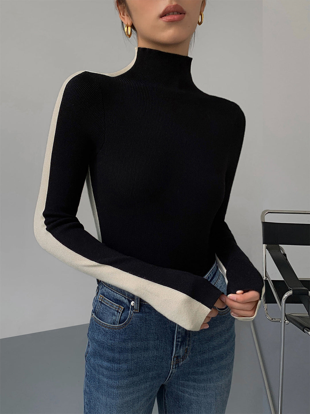 Elegante zwarte dames gebreide trui met hoge kraag en subtiel ribpatroon, perfect voor winter en herfst.