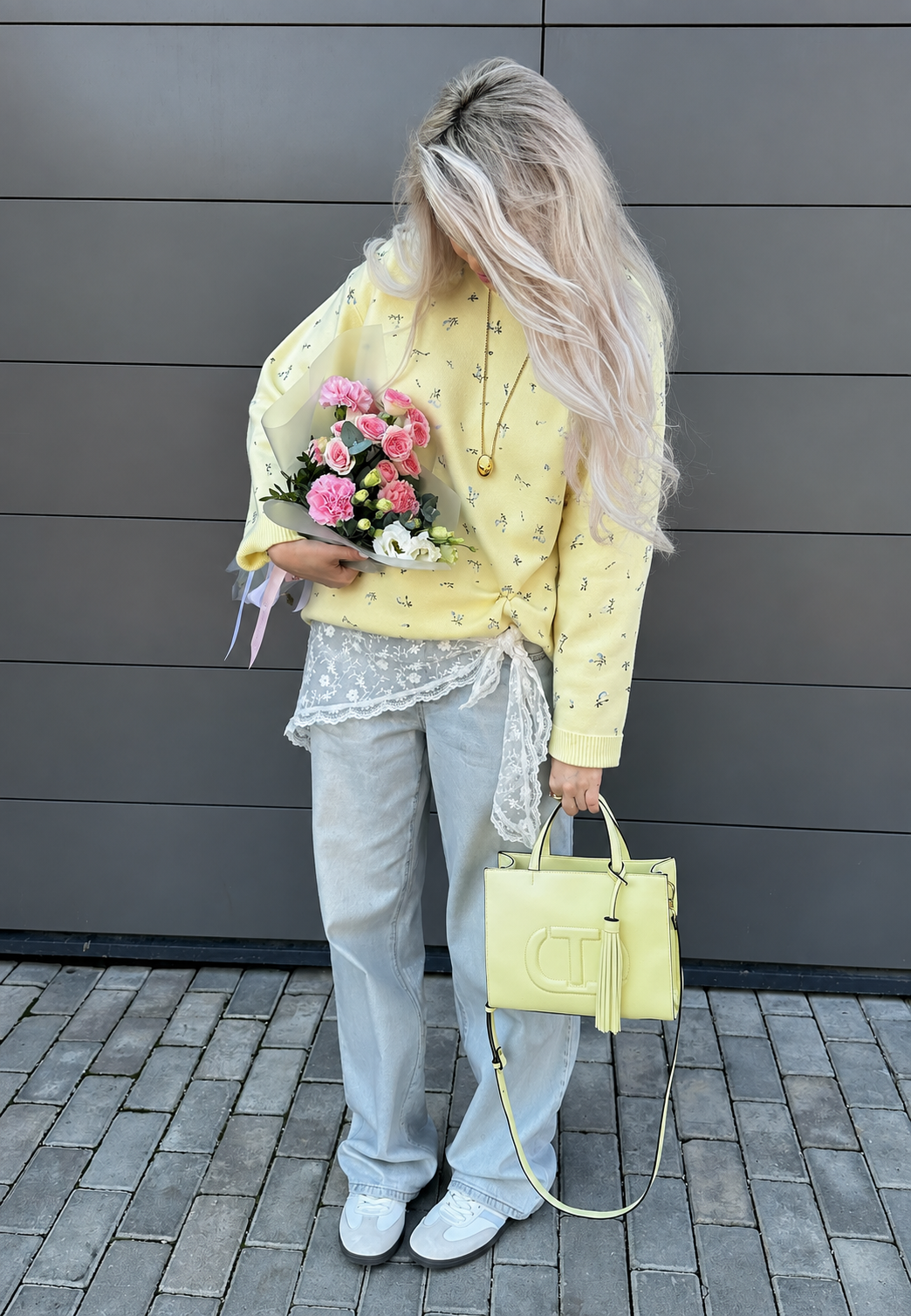 Model draagt gele oversized dames trui met bloemenprint en lange mouwen. Casual en comfortabele dameskleding.