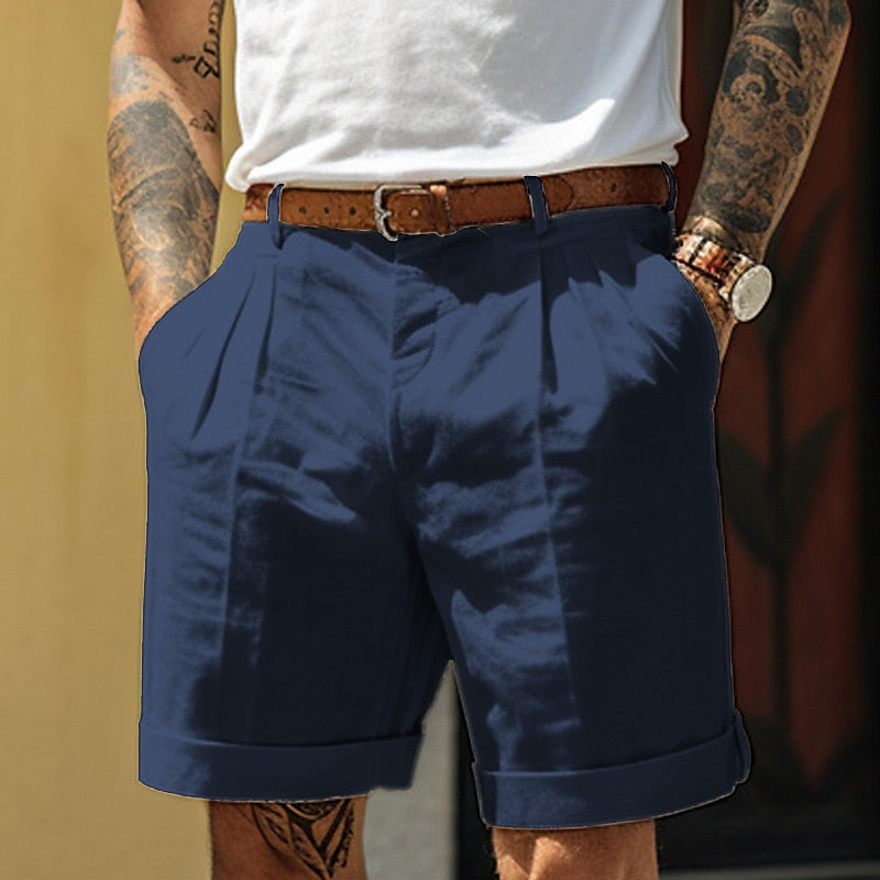 Blauwe heren chino shorts met geplooide voorkant en omslagzoom, gedragen door model voor casual zomerstijl.