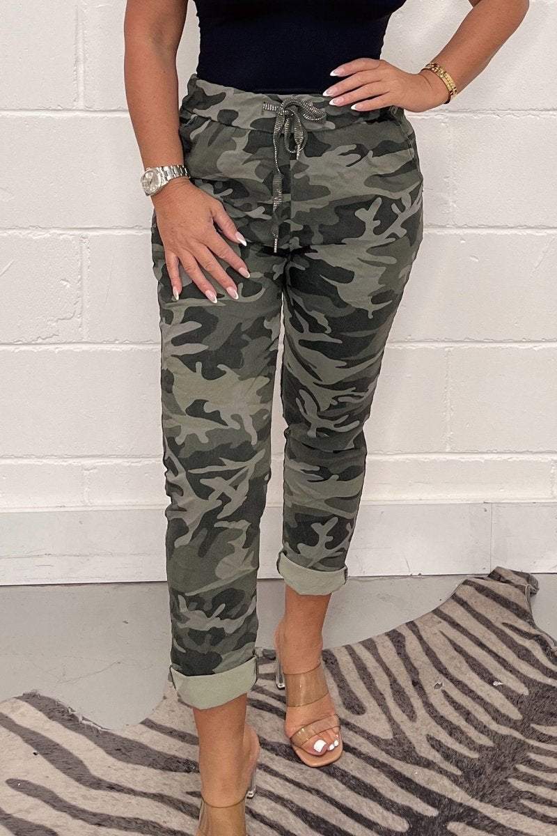 Vrouwelijke camouflage broek met legerprint, gedragen met trendy top. Stijlvolle en comfortabele damesbroek.