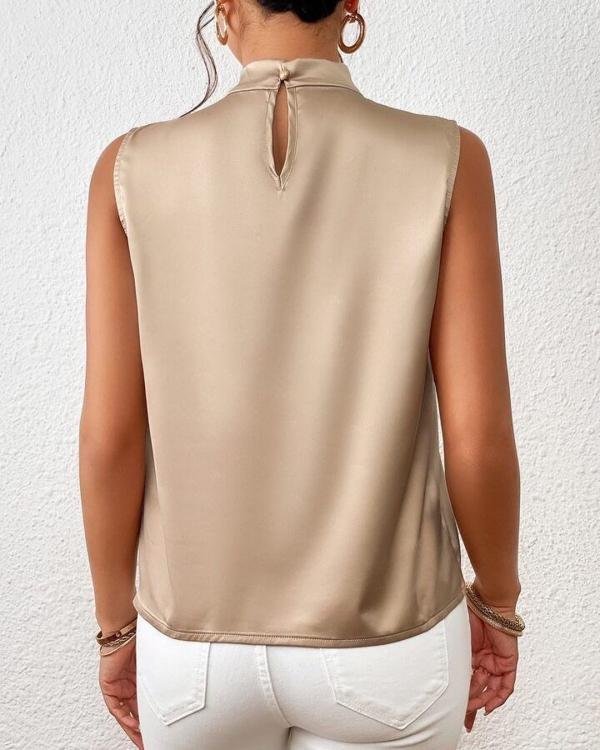 Modieuze mouwloze dames top in abrikoos met gedraaide hals. Vrouwelijke zomerblouse voor een chique look.