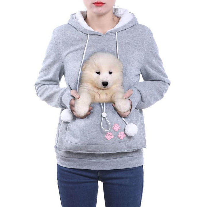 Blij persoon draagt kat in CozyPurr haarvrije kattenzak hoodie, genietend van elkaars warmte en comfort.
