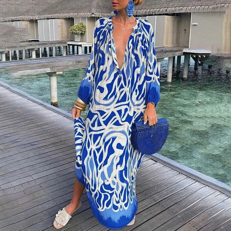 Dame draagt een stijlvolle maxi jurk met lange mouwen, bohemian print en v-hals, lopend op het strand.