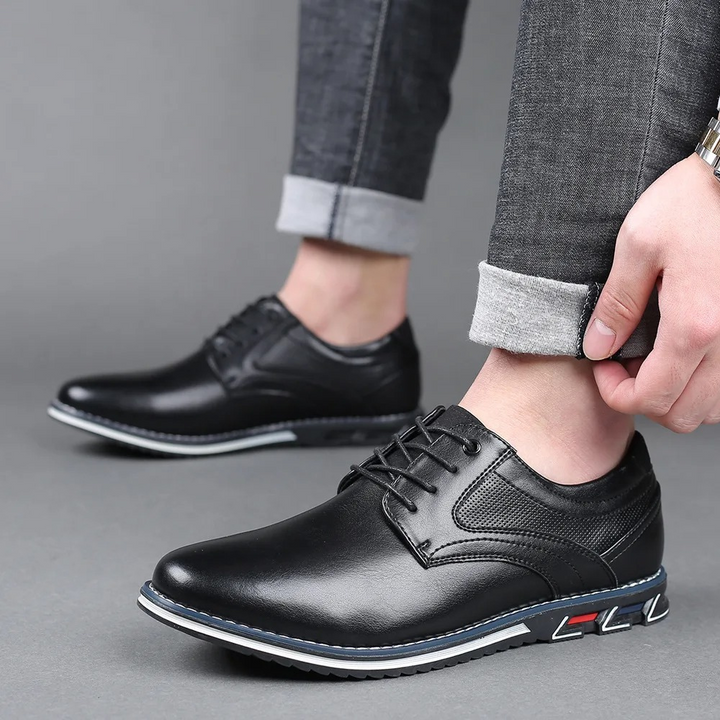Detail van bruine leren herenschoenen; nette, handgemaakte stiksels voor een zakelijke look.