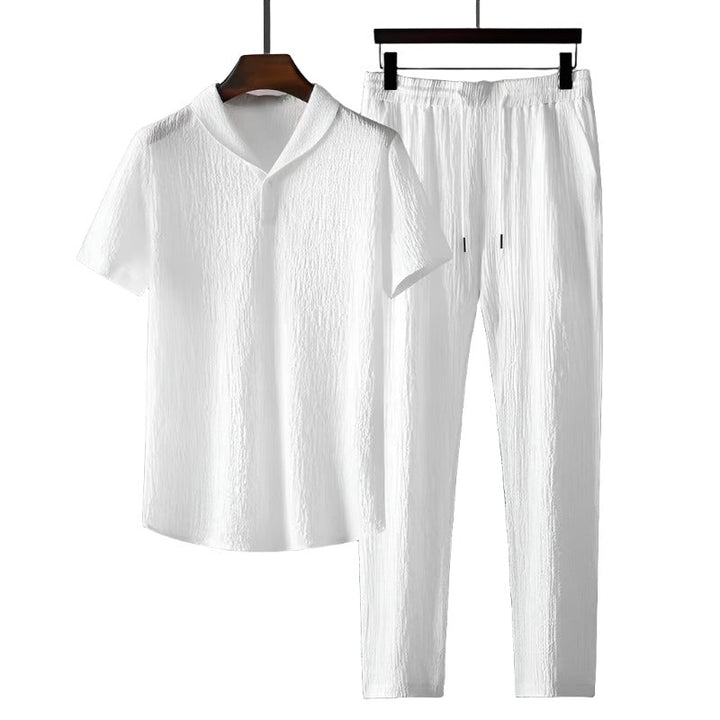 Man model draagt comfortabele heren katoenen poloshirt en pantalon set. Ideaal voor ontspannen lente/zomer stijl.