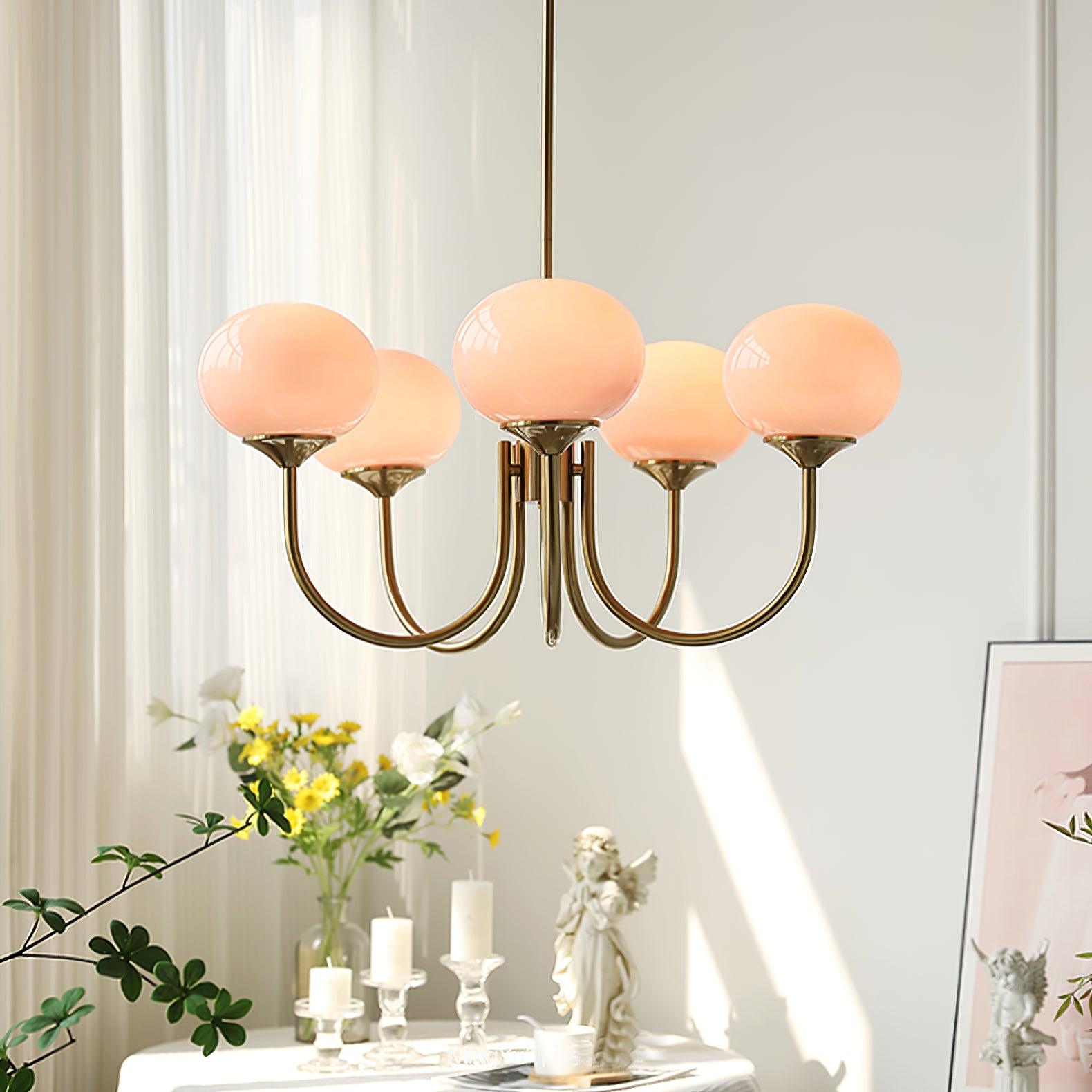 "Moderne kroonluchter met gouden afwerking en roze glazen kappen, geschikt voor LED verlichting in eigentijds interieur."