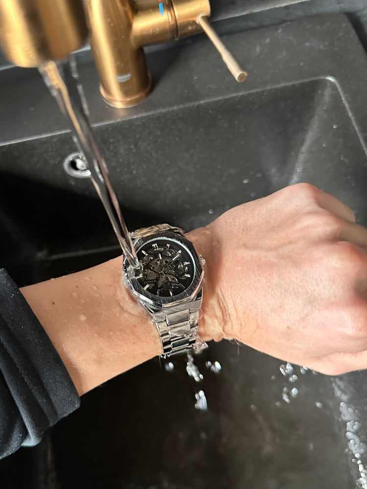 Luxe zilverkleurig automatisch herenhorloge met zwarte wijzerplaat, waterdicht en tijdloos.