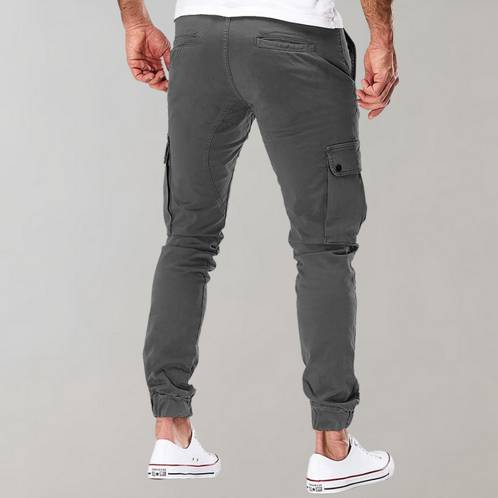 Model draagt een grijze Heren Cargo Broek Noah, toont de casual pasvorm en stijl.