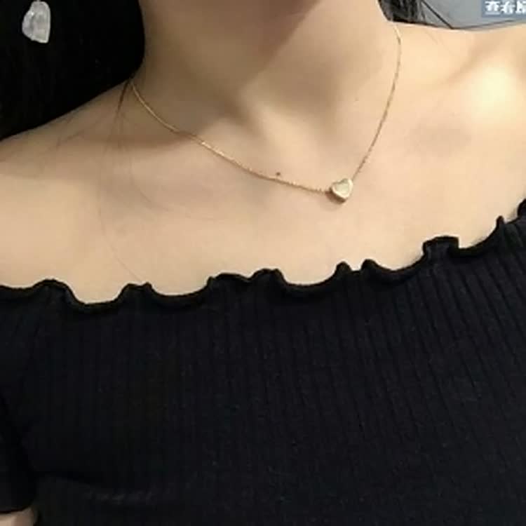 Detailfoto van een glanzende zilverkleurige damesketting met kleine hartje hanger.