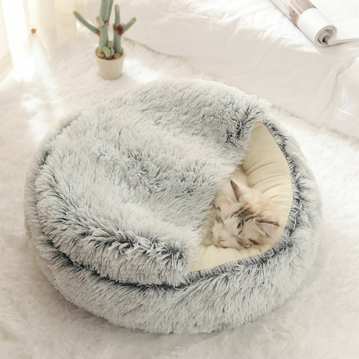 Blije kat slaapt diep in zachte pluchen katten slaapmand, genietend van warmte en privacy.