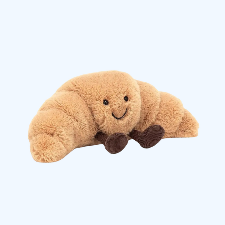 Zacht pluche croissant kussen in babykamer, perfect als speelknuffel of decoratief element voor kinderen.