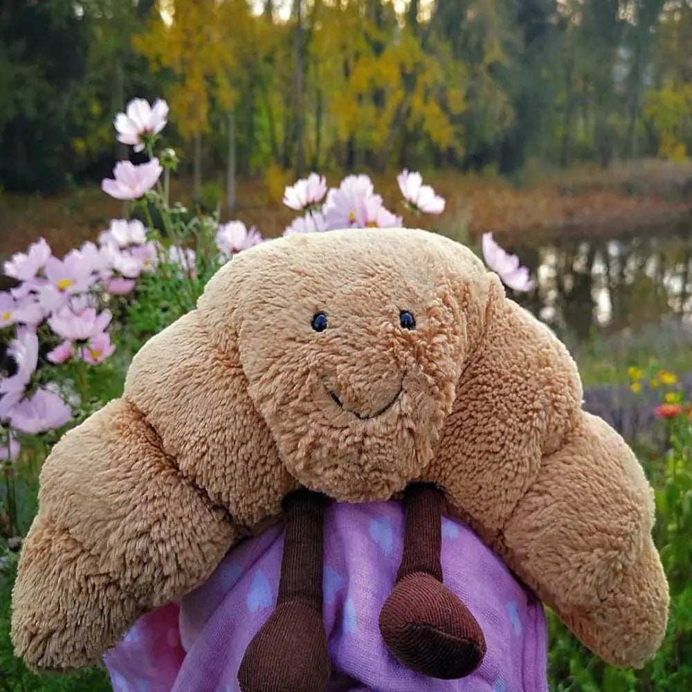 Decoratief croissant knuffelkussen, zacht pluche en lachend gezichtje, perfect cadeau en kinderkamer accessoire.