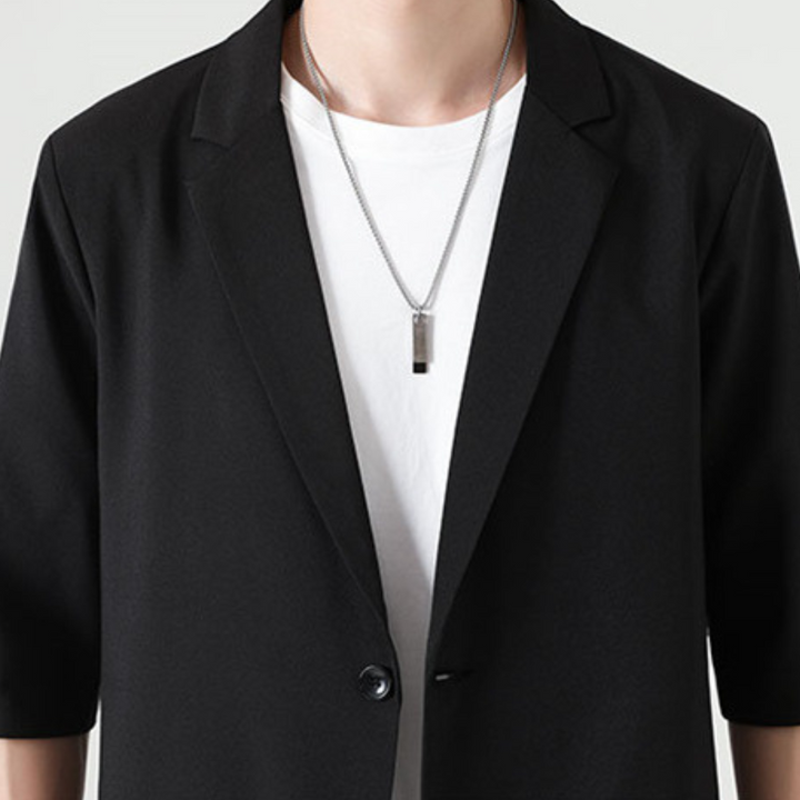 Man draagt complete zwarte tweedelige heren smart casual set; moderne en elegante kleding.