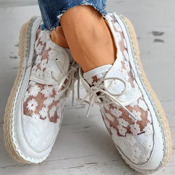 Zijaanzicht van orthopedische dames sneakers. Benadrukt het geborduurde patroon en de comfortabele platte zool.