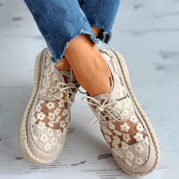 Close-up van het elegante borduurwerk op beige orthopedische dames sneakers, modieus en comfortabel.