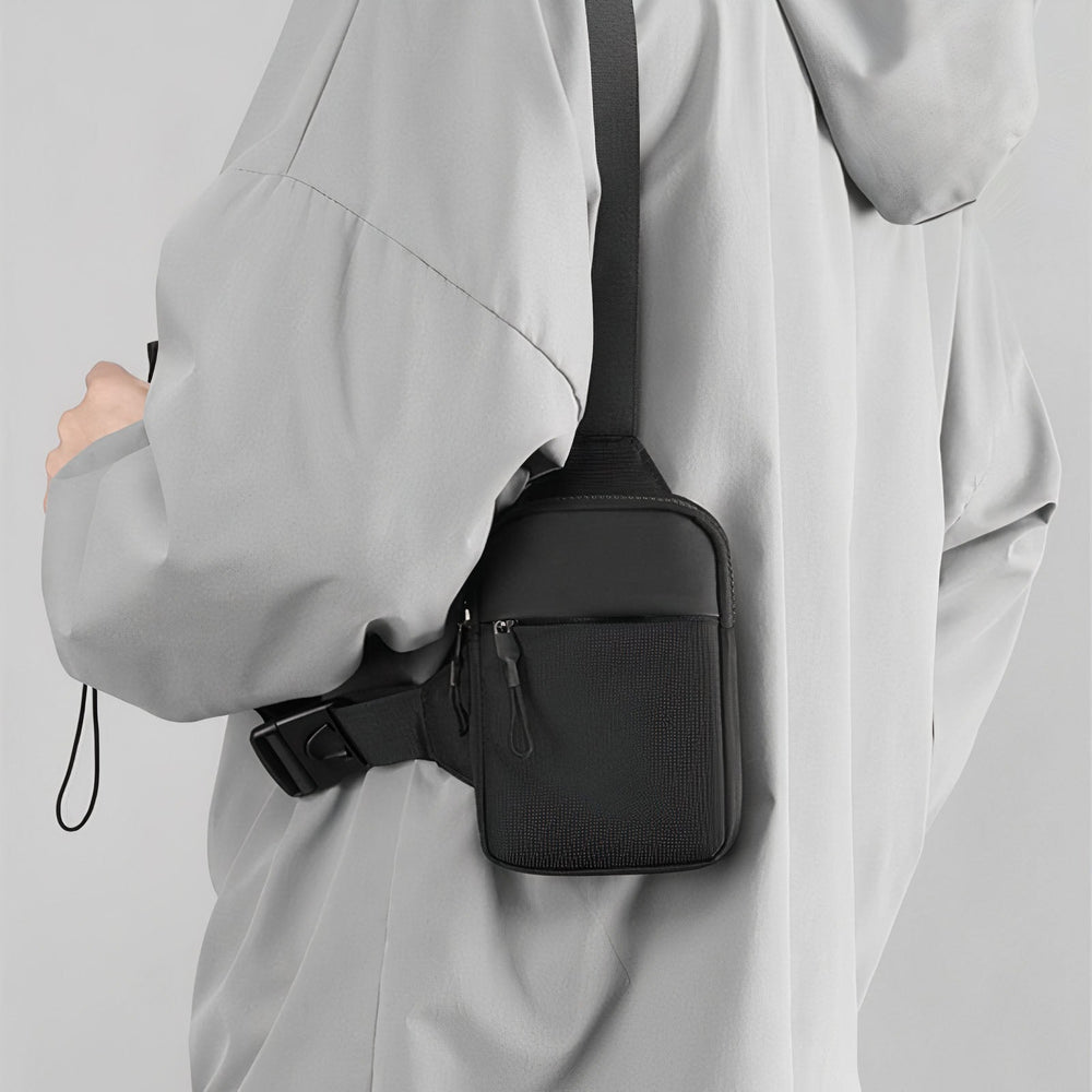 Man draagt zwarte slingbag schoudertas comfortabel over schouder, perfect voor dagelijkse avonturen.