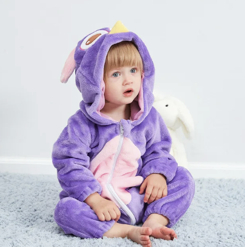 Blije baby in warme fleece overall met dierenontwerp, spelend op de grond.