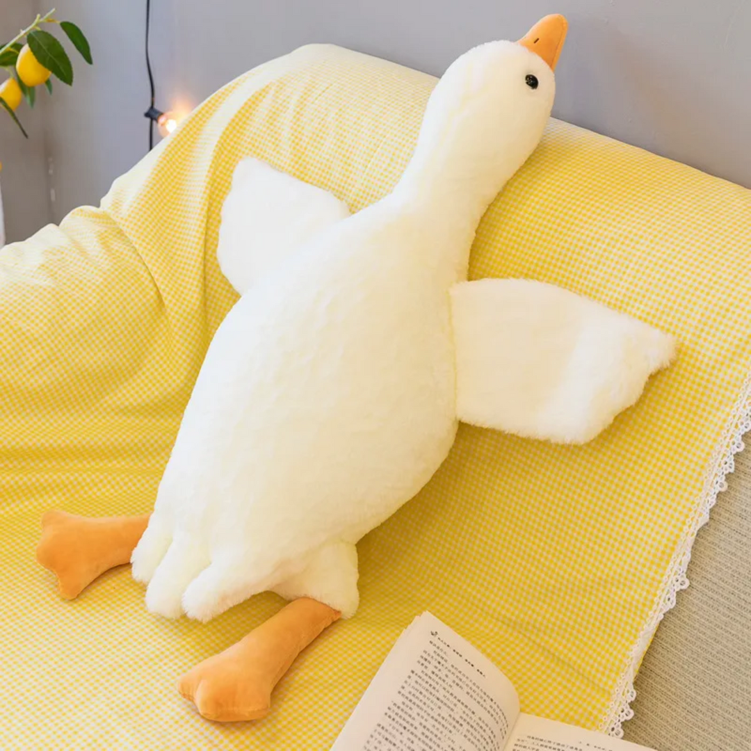 Witte pluche gans kussen op kinderbed. Knuffel voor decoratie, speelplezier en zacht comfort voor kinderen.