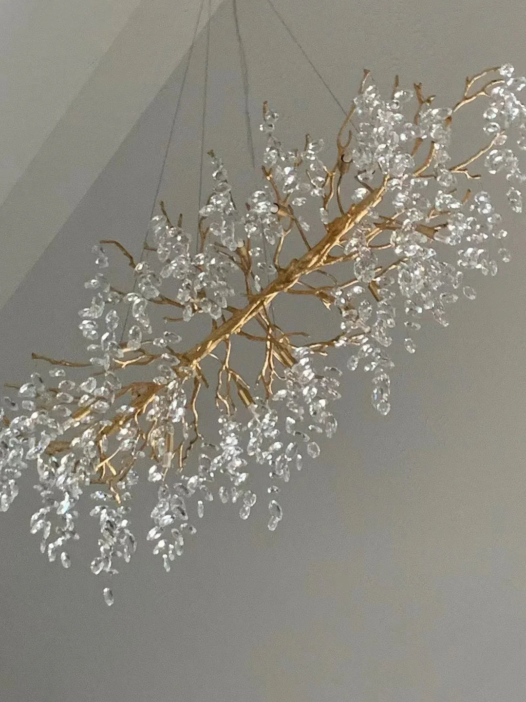 Moderne gouden kroonluchter Aurelia, kristal en bladontwerp. Voegt elegantie toe.