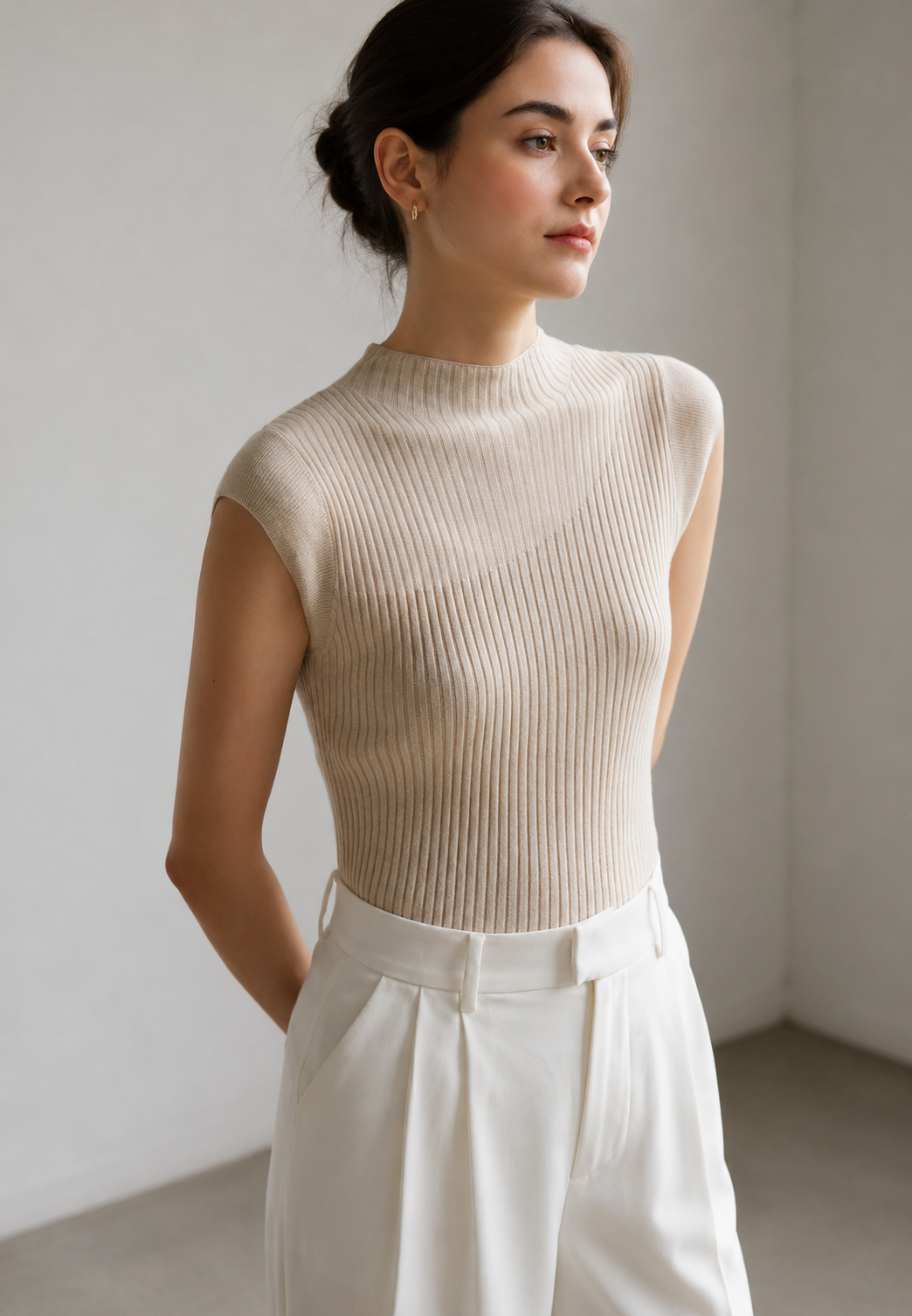 Model draagt stijlvolle mouwloze ribbel top met hoge kraag. Modieus en comfortabel voor lente/zomer.