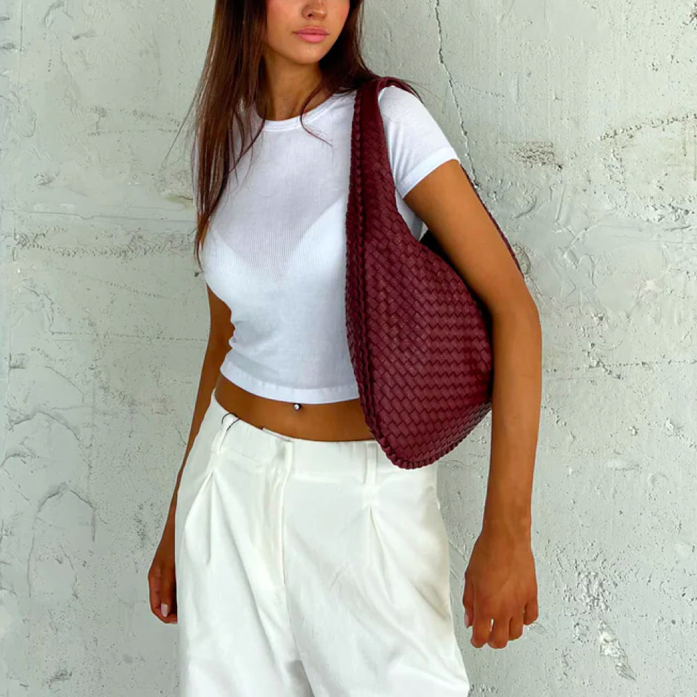 Damesmodel draagt de 'Elise' stijlvolle geweven tote bag over de schouder, een elegante handtas.