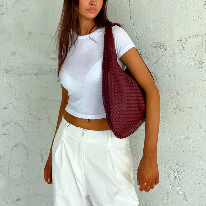 Damesmodel draagt de 'Elise' stijlvolle geweven tote bag over de schouder, een elegante handtas.