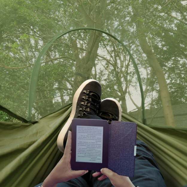 Kampeer hangmat in bos: Persoon ontspant in groene ultralichte hangmat met insectennet, perfect voor outdoor reizen.