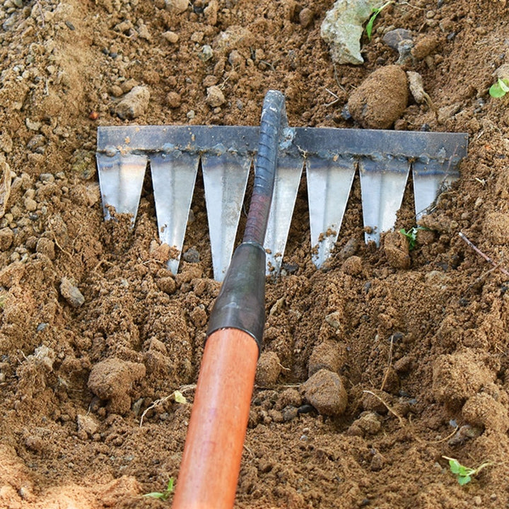 Een tuinier gebruikt de tuinhulp onkruidhark voor efficiënt tuinonderhoud in de moestuin.