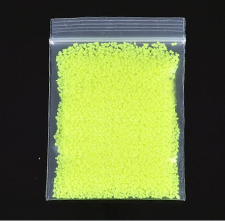 Hand die lichtgevend poeder strooit over een DIY-project, voor een betoverend glow in the dark effect.