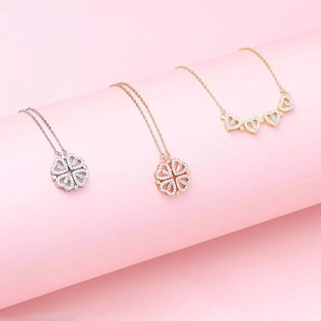 Close-up van glinsterende zirkonia klavertje vier en dubbele hartjes hanger aan een roestvrij stalen dames ketting.