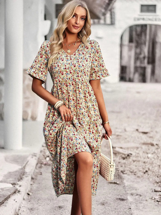 "Zomerjurk met bloemenpatroon en V-hals in abrikoos; elegante, casual damesjurk voor een stijlvolle zomerlook."