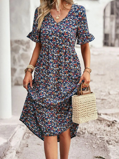 "Zomerjurk met bloemenpatroon en V-hals in abrikoos; elegante, casual damesjurk voor een stijlvolle zomerlook."